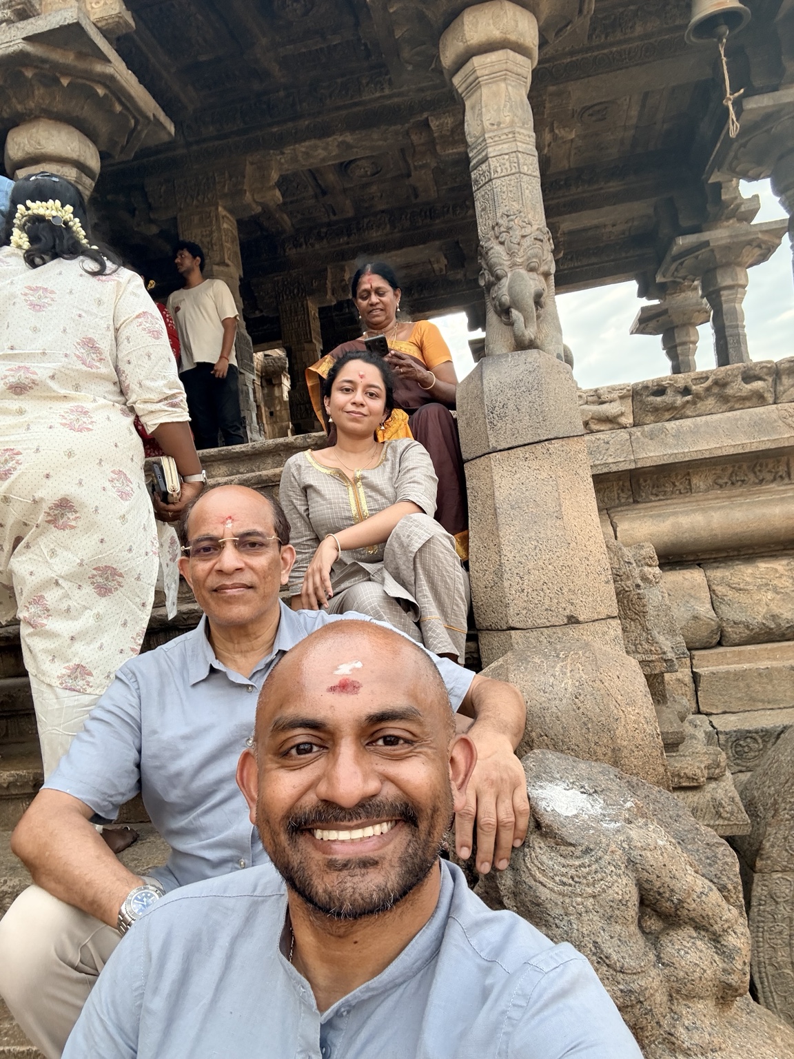 Vik smiling with three adult family members on the steps of a temple