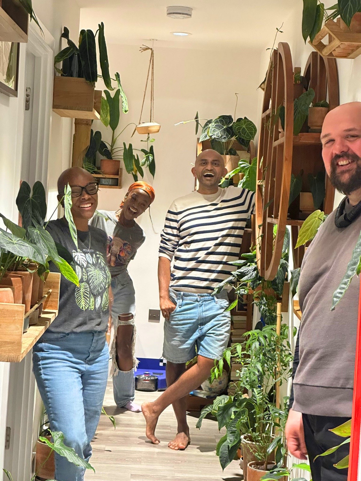 Vik and three adult friends laughing together in a room filled with houseplants