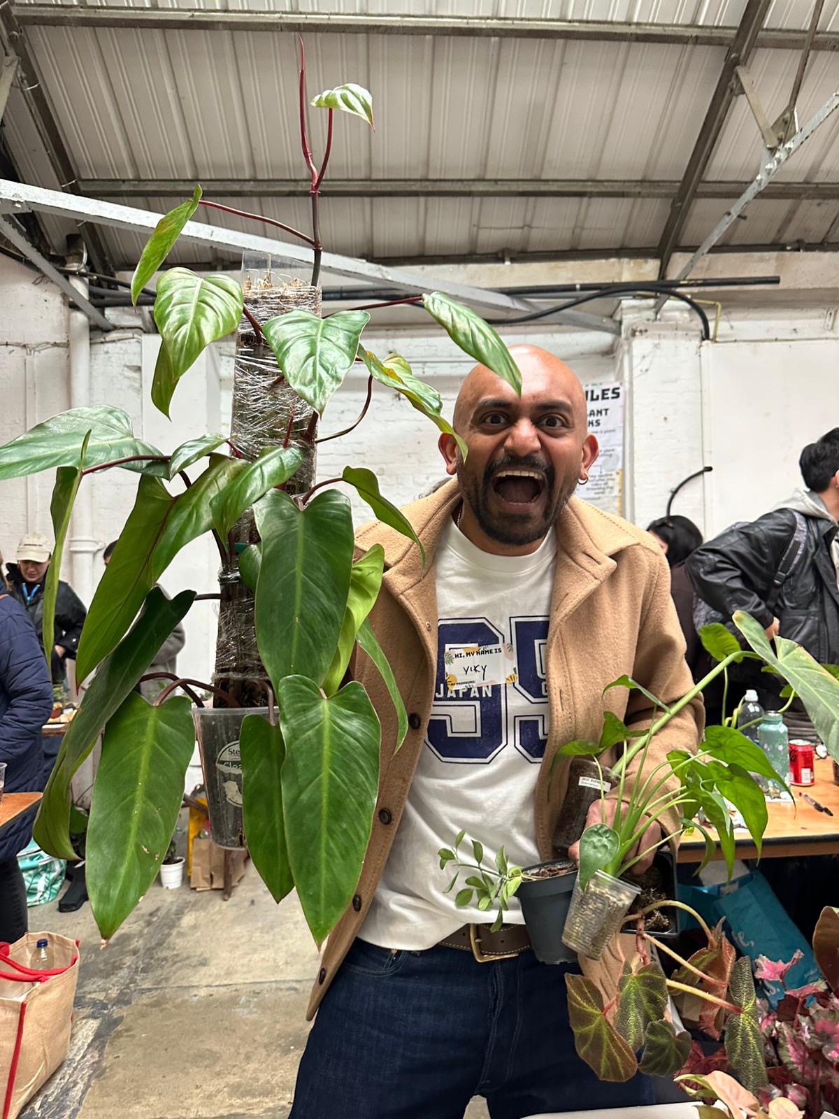Vik smiling behind a large climbing aroid at a plant gathering